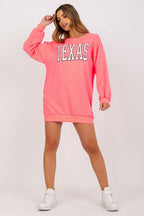 Woman wearing a pink 'TEXAS' sweatshirt dress on a white background