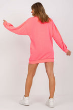Person wearing a bright pink sweatshirt dress on a white background