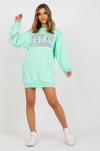 Person wearing a mint green sweatshirt dress with 'TEXAS' text on a white background