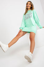 Woman wearing a mint green 'Texas' sweatshirt and shorts set on a white background