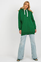 Woman wearing a green hoodie and light blue jeans on a white background