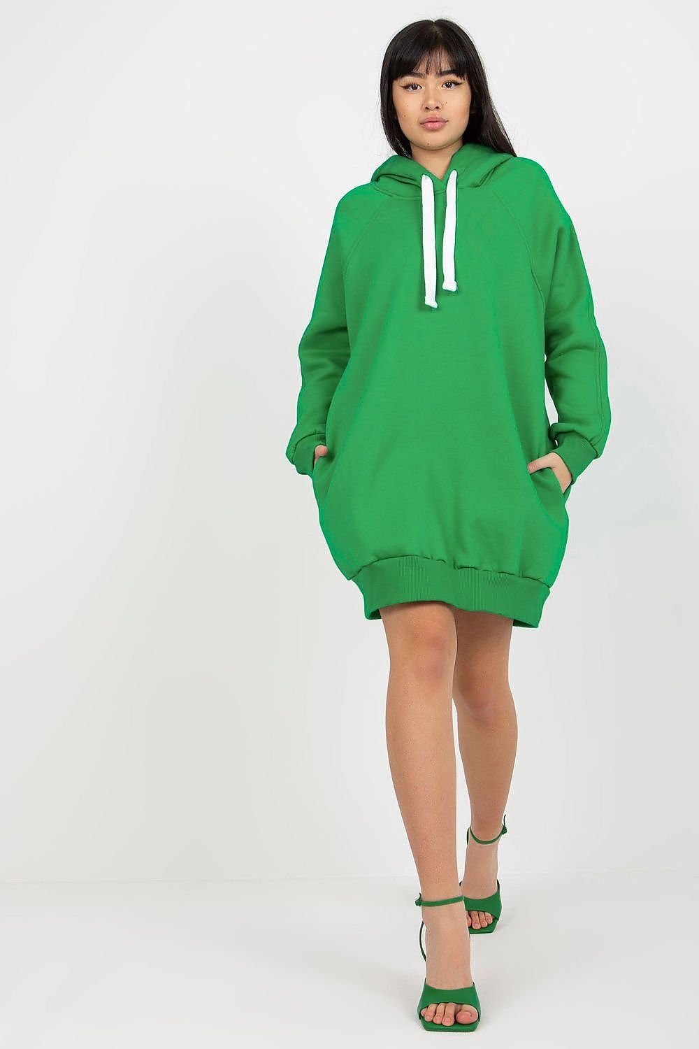 Person wearing a green hoodie dress on a white background
