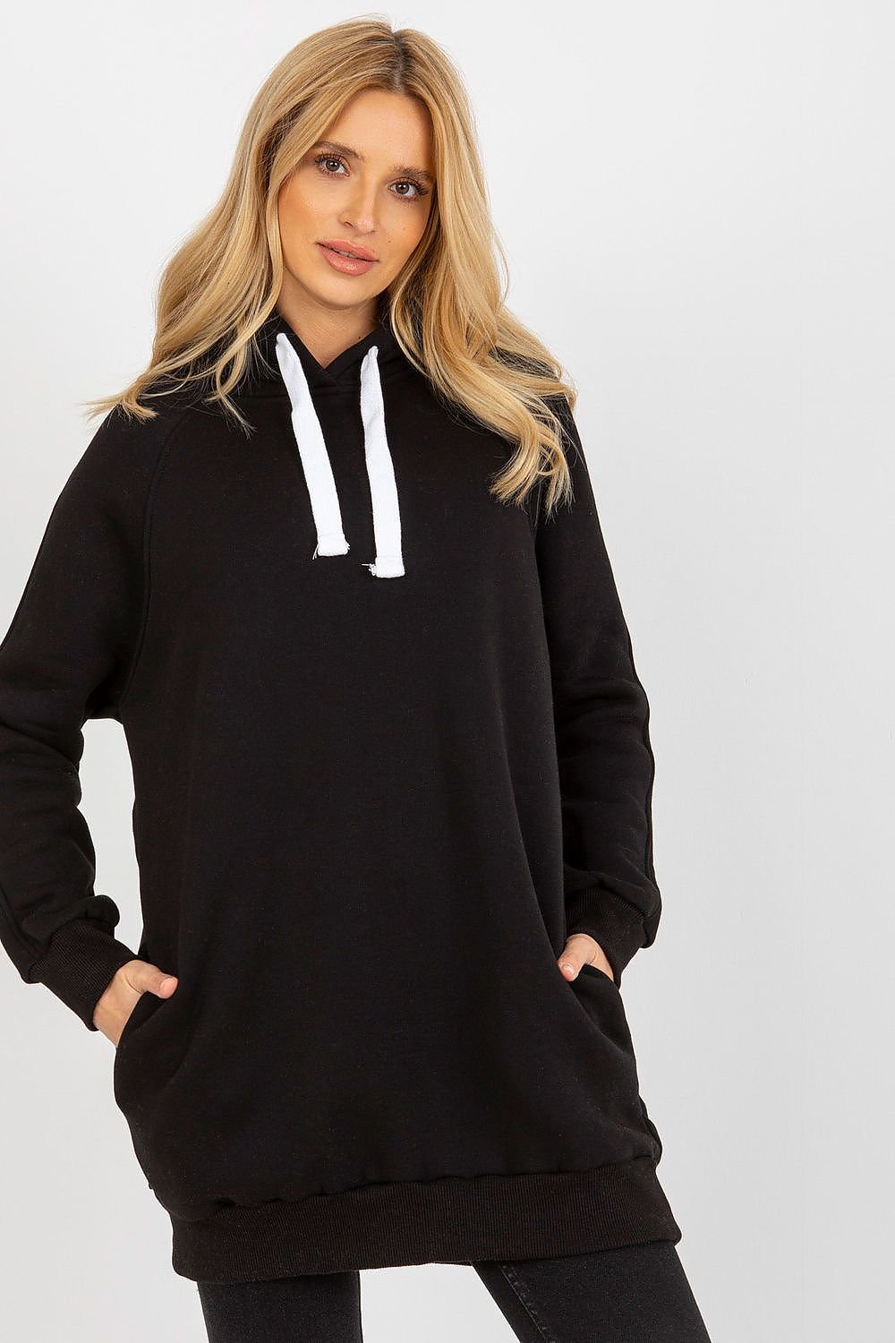 Woman wearing a black hoodie with white drawstrings on a light gray background