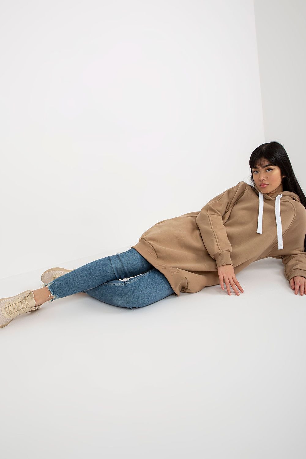 Person wearing a brown hoodie and blue jeans on a white background