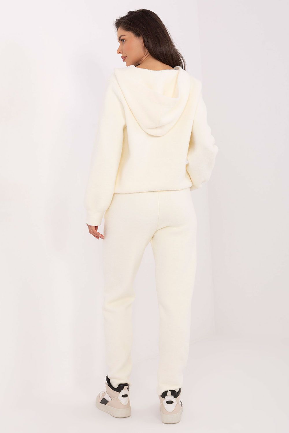 Person wearing a cream-colored hoodie and pants on a white background