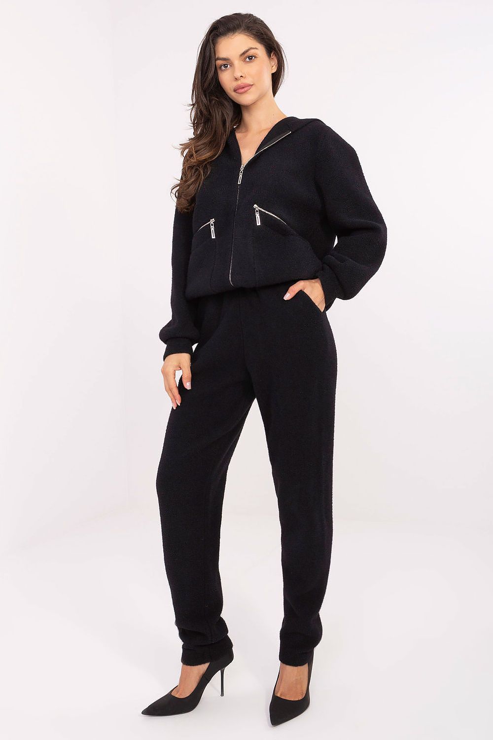 Woman wearing a black zip-up hoodie and pants on a white background