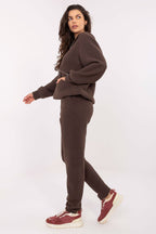 Woman wearing a brown tracksuit with maroon sneakers on a white background