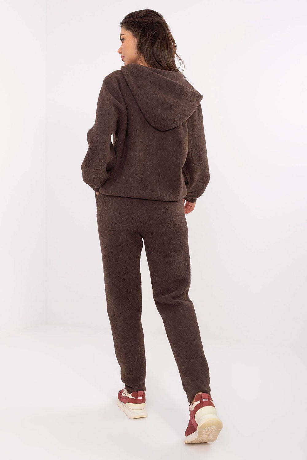 Person wearing a brown tracksuit on a white background