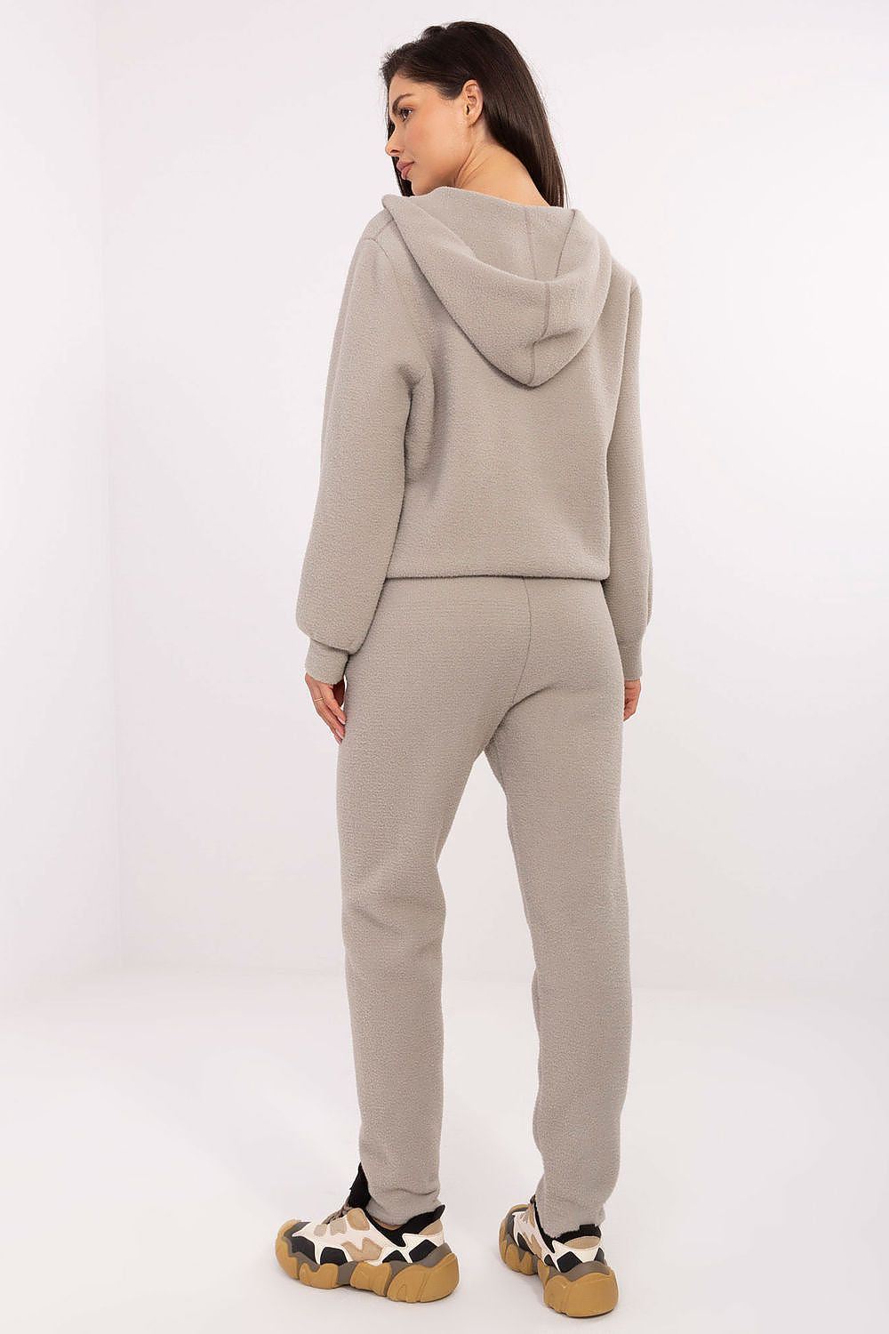 Person wearing a beige tracksuit on a white background