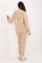 Person wearing a beige tracksuit on a white background