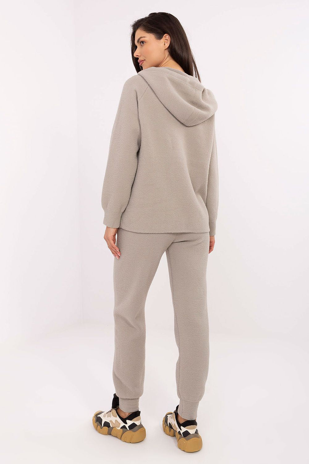 Woman wearing a beige tracksuit on a white background