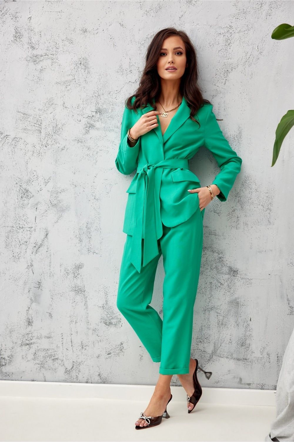 Woman wearing a green suit against a gray concrete wall.