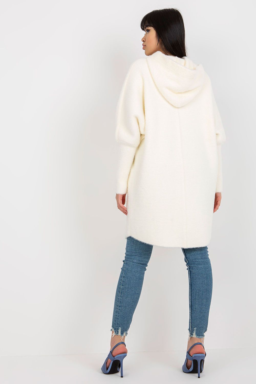 Woman wearing a white hooded coat and blue jeans on a white background