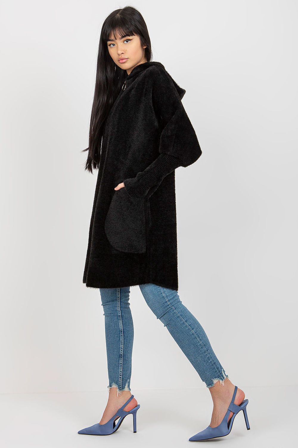 Woman wearing a black coat, blue jeans, and high heels on a white background