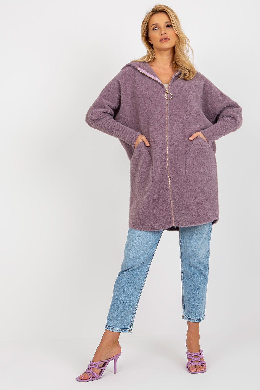 Woman wearing a long, hooded purple jacket and blue jeans on a white background