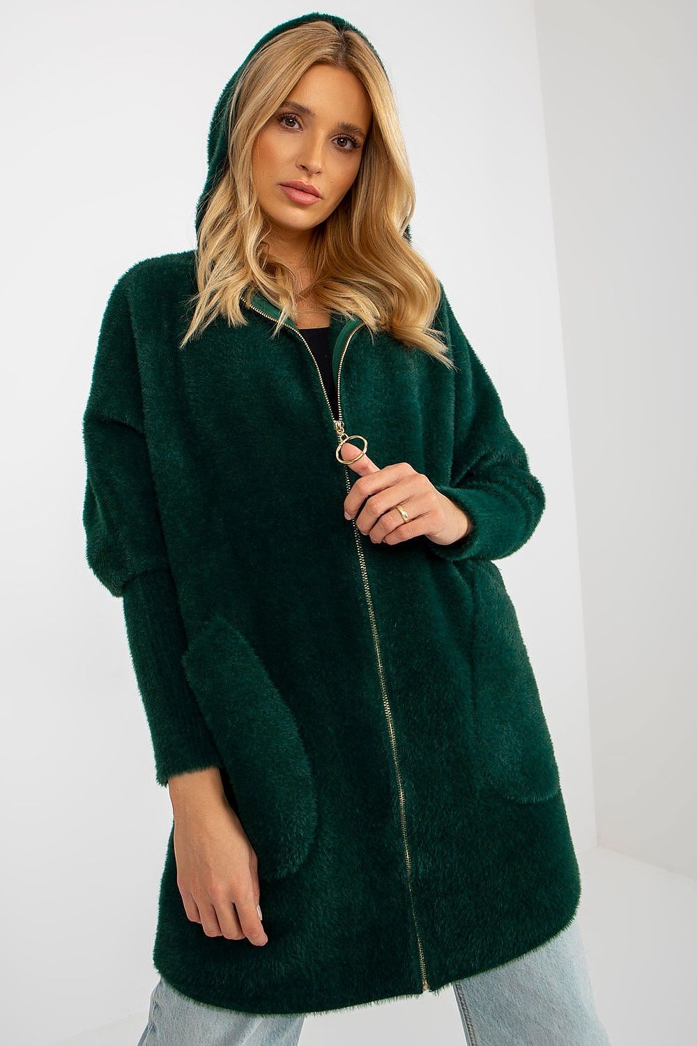 Woman wearing a green hooded coat against a white background