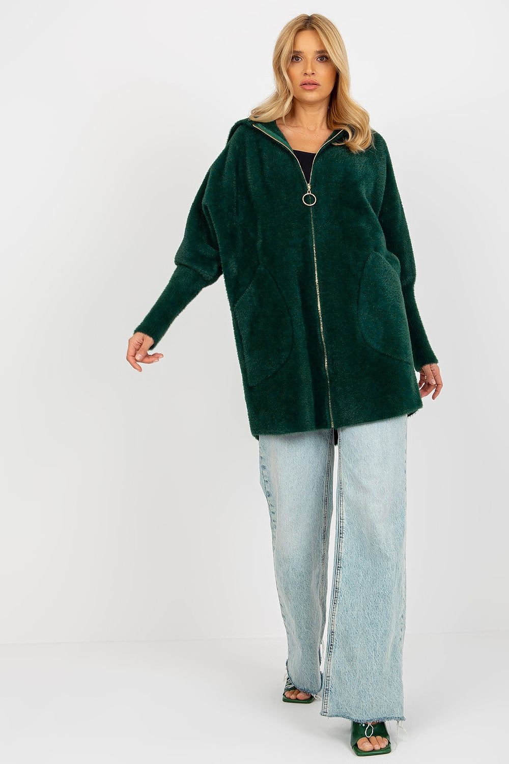 Woman wearing a green hooded jacket and light blue jeans on a white background
