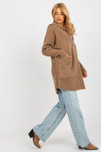 Woman wearing a brown coat and light blue jeans on a white background