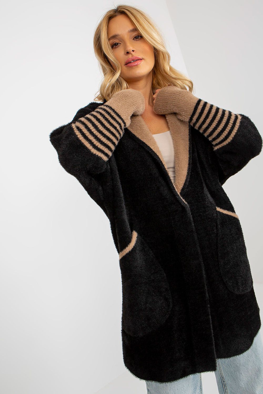 Woman wearing a black cardigan with beige accents on a white background