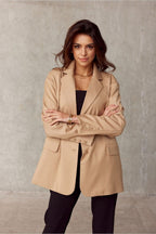 Woman wearing a beige coat against a plain background