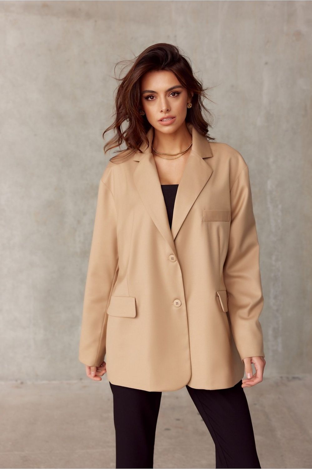 Woman wearing a beige coat against a plain background