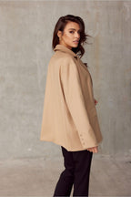 Woman wearing a beige coat against a plain background