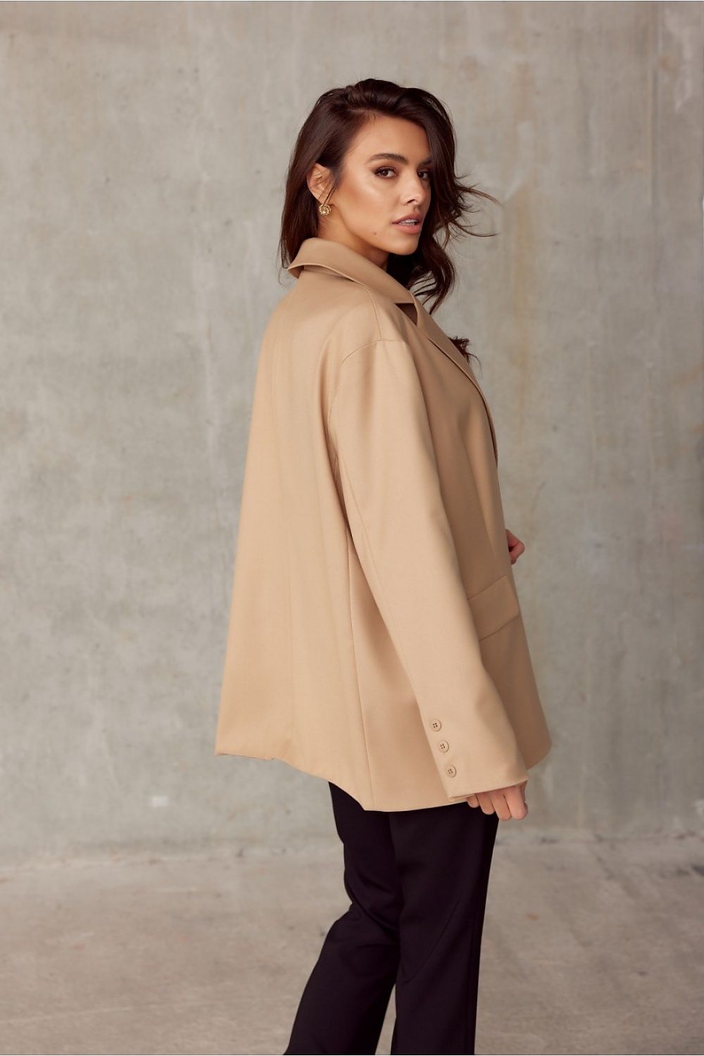 Woman wearing a beige coat against a plain background
