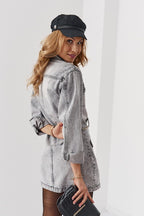 Woman wearing a gray denim jacket and black cap against a white background