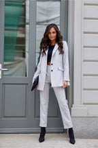 Woman in a gray pinstripe suit standing in front of a gray door.