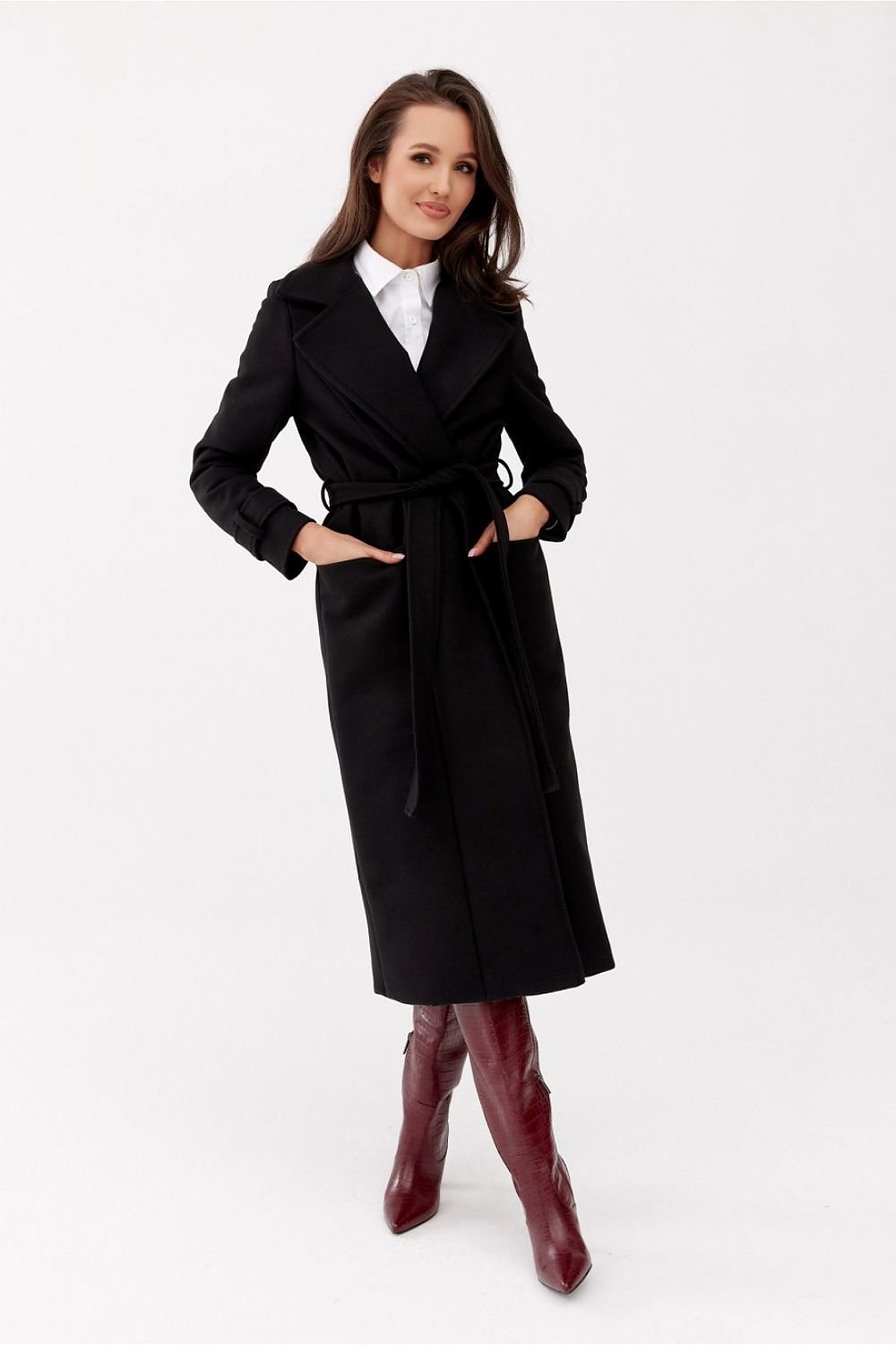 Woman wearing a black coat and red boots on a white background
