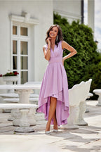 Woman in a purple dress standing outdoors near white columns.
