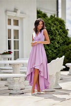 Woman in a purple dress standing outdoors near a white building.