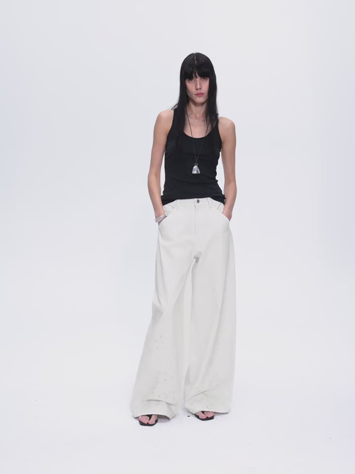 Woman wearing a black tank top and white pants on a white background