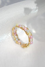 Gold and pink beaded ring on a white fabric background