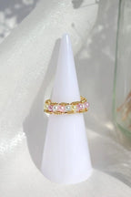 Two pearl rings on a white cone-shaped stand with a light background