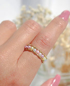 Close-up of a hand wearing a pearl and gold ring with 'Divine Dulcet Fine Jewelry' branding.