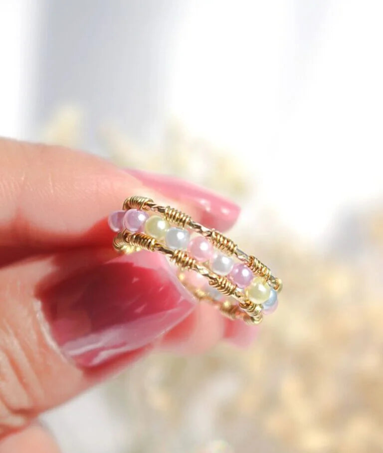 Gold and pearl ring held by a hand with 'Divine Dulcet Fine Jewelry' branding.