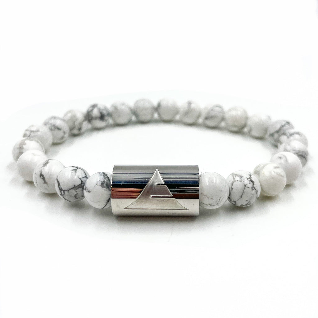 Bracelet with white beads and silver cylindrical clasp on a white background