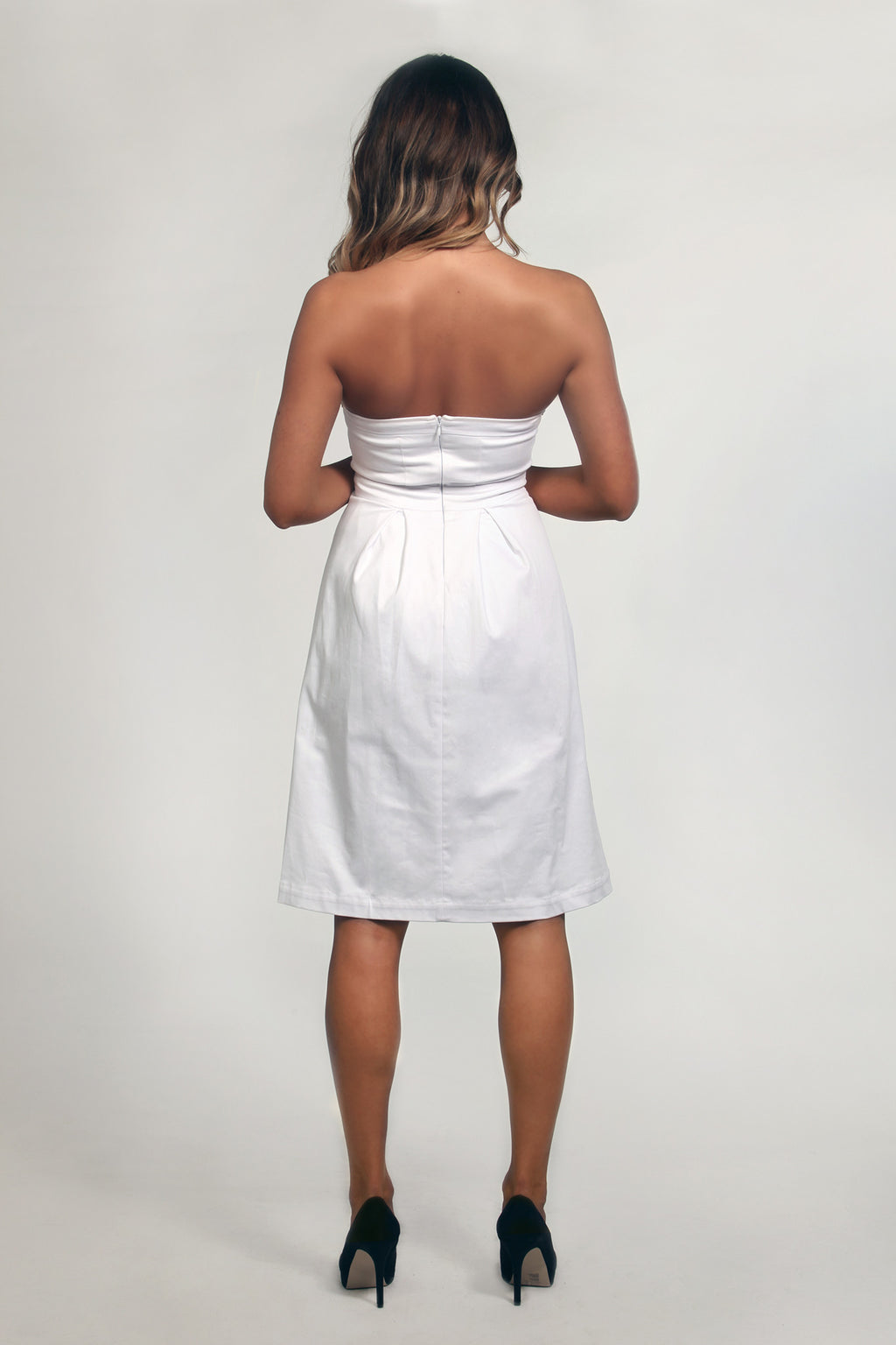 Woman wearing a strapless white dress on a plain background