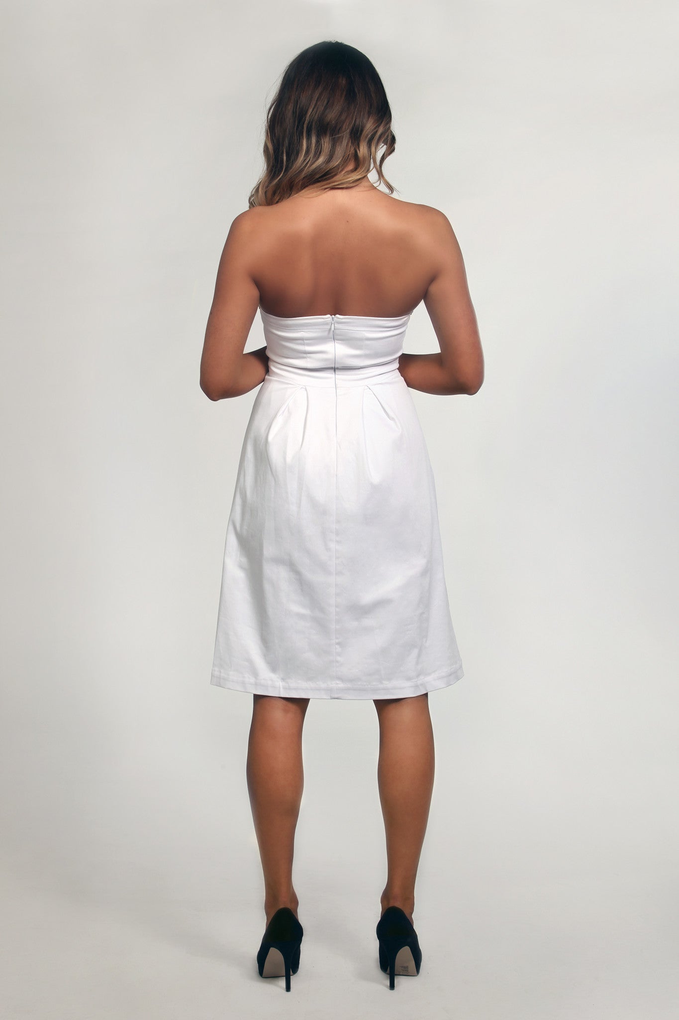 Woman wearing a strapless white dress on a plain background