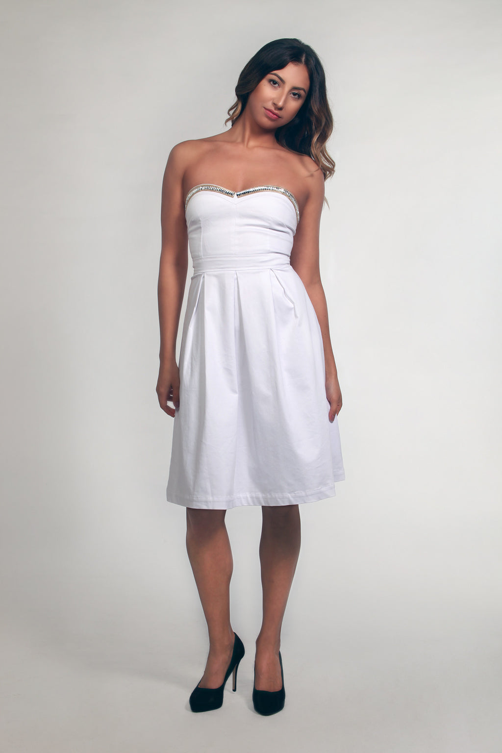 Woman wearing a white strapless dress on a plain background