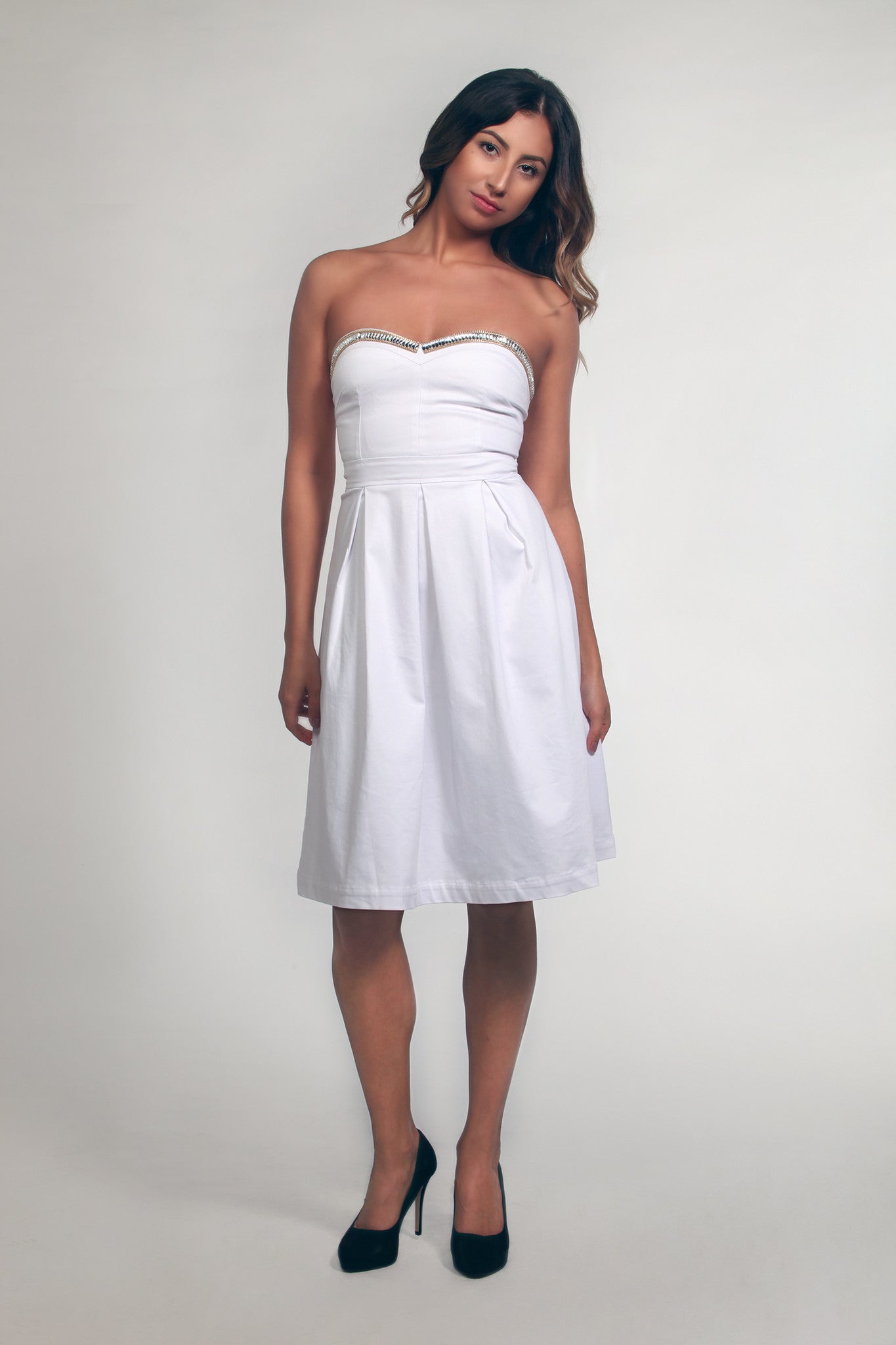 Woman wearing a white strapless dress on a plain background