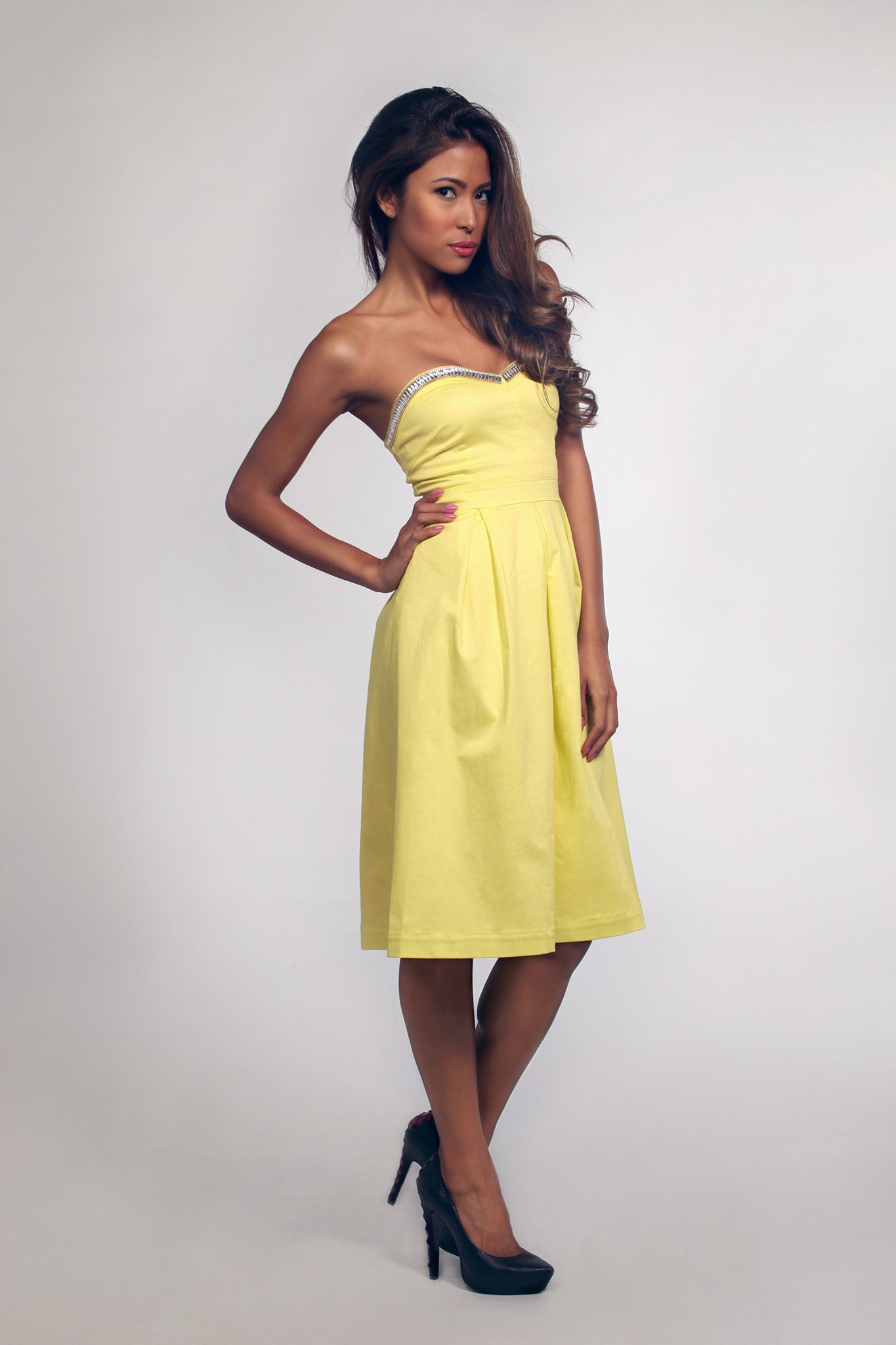Woman wearing a yellow strapless dress on a white background