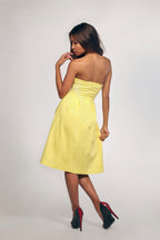 Woman wearing a yellow strapless dress on a plain background