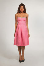 Woman wearing a pink strapless dress with a white background