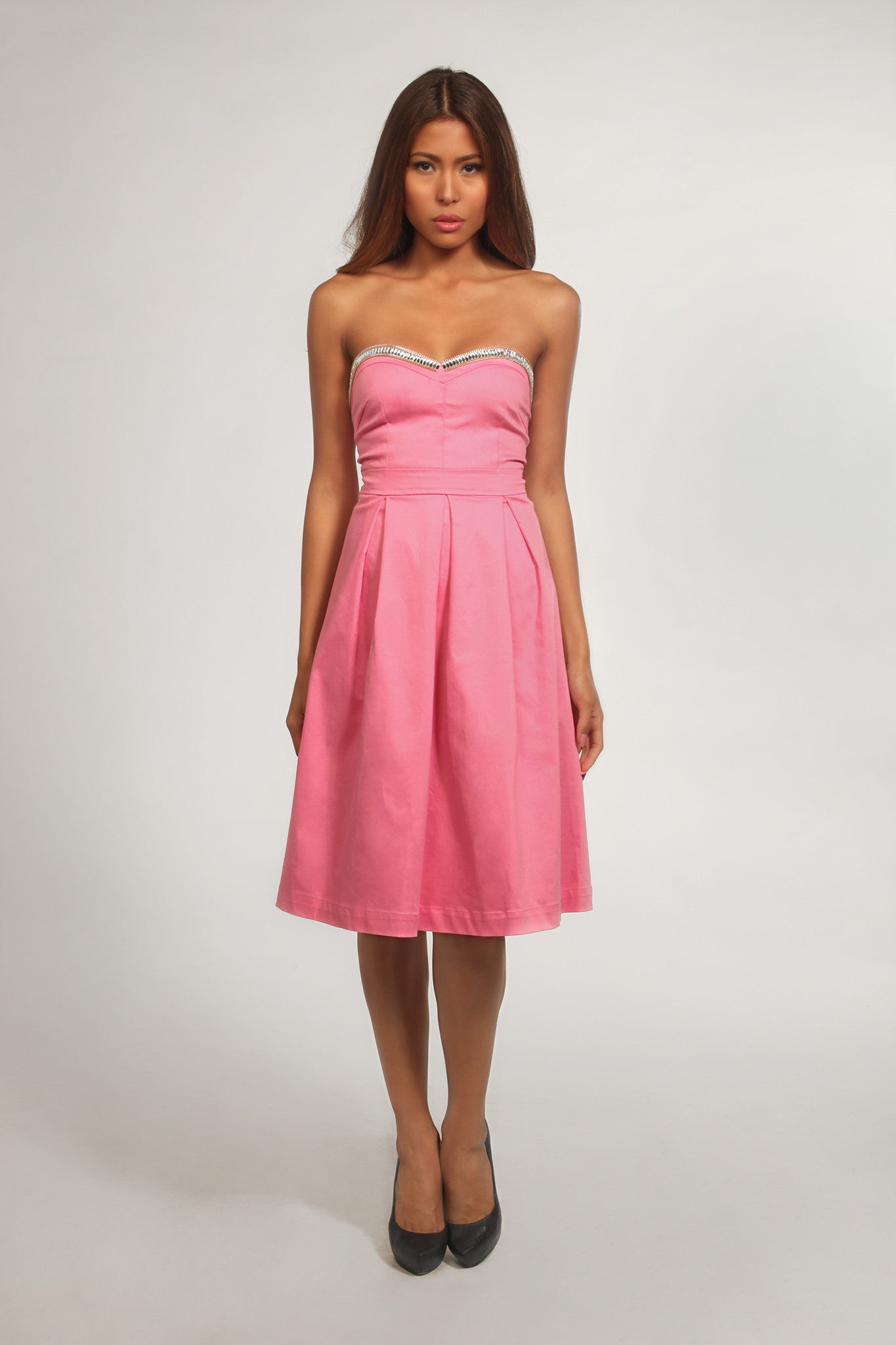 Woman wearing a pink strapless dress with a white background