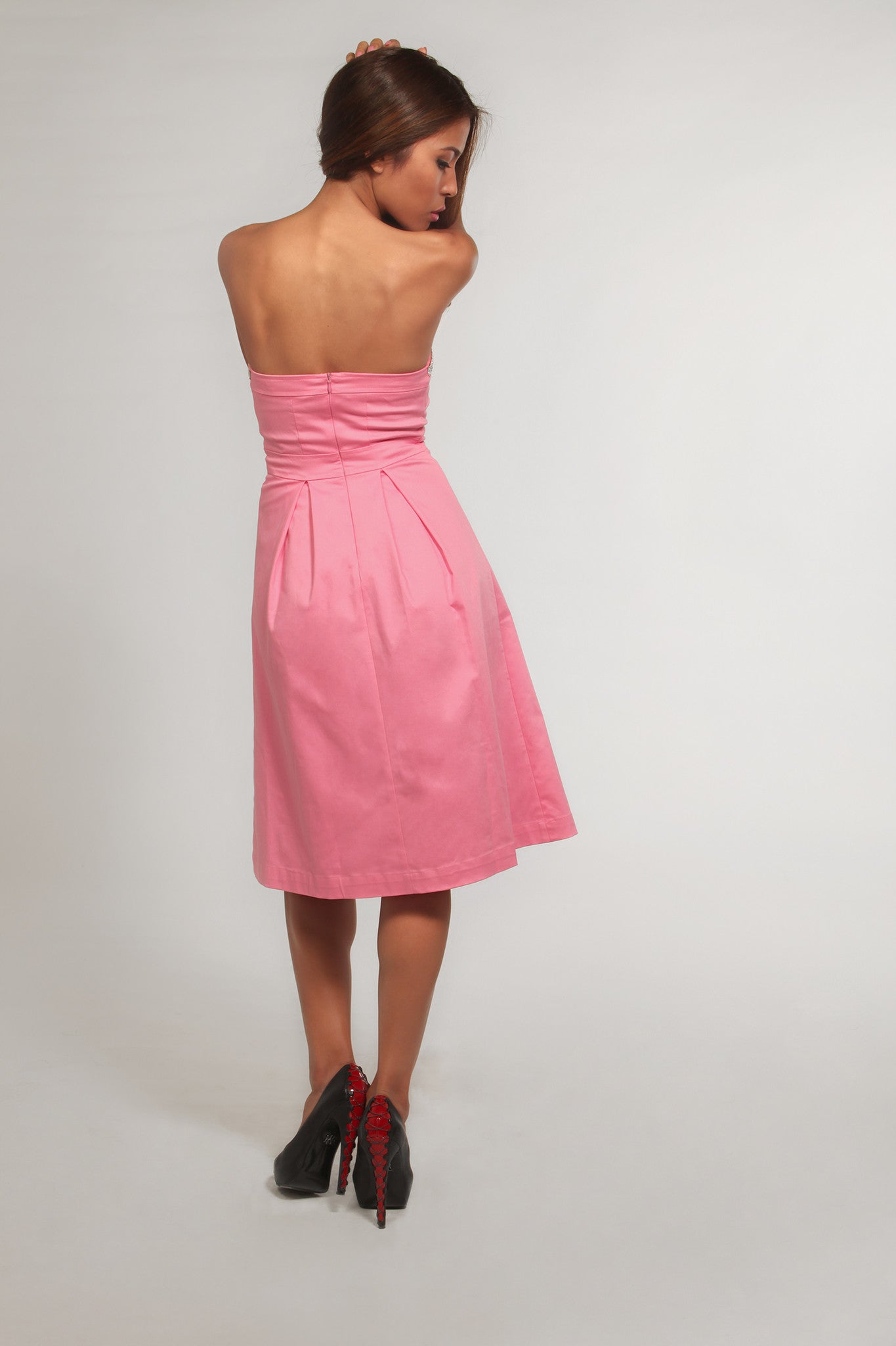Woman wearing a pink strapless dress on a white background