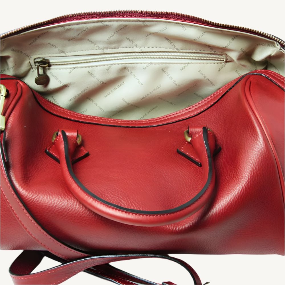 Elegant full-grain leather shoulder bag, 31x20x18 cm, with double handles, two interior zipped pockets, adjustable/removable strap, bottom feet, and polyester lining.