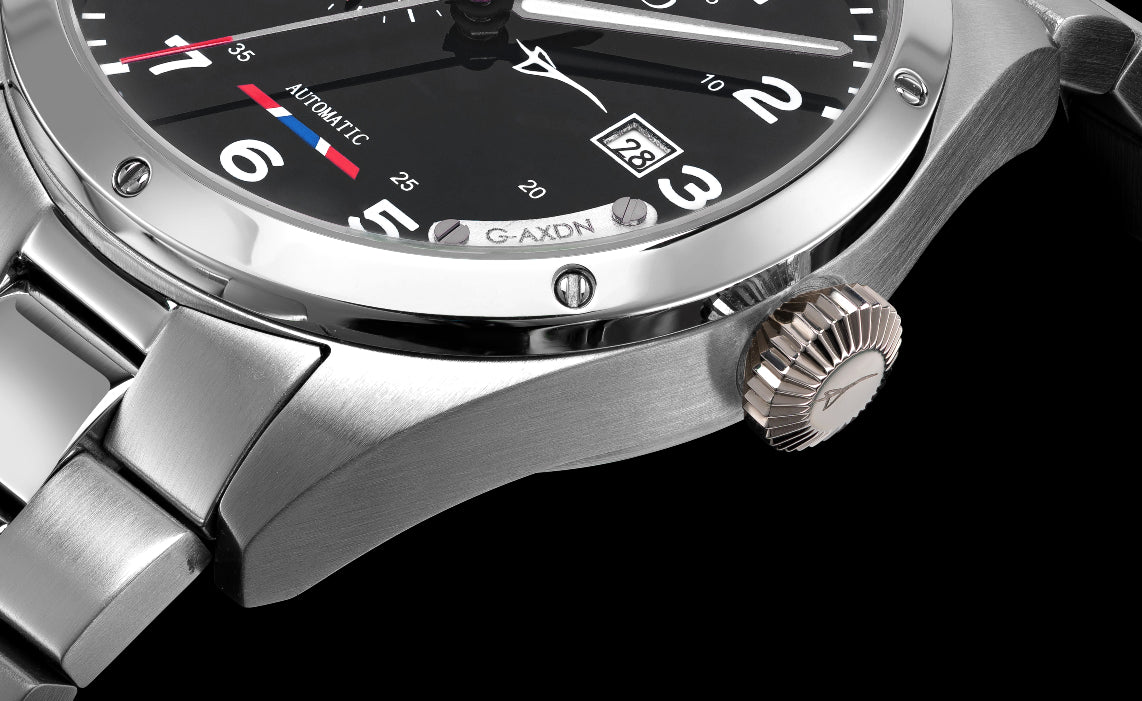 Close-up of a silver watch with a black face on a black background